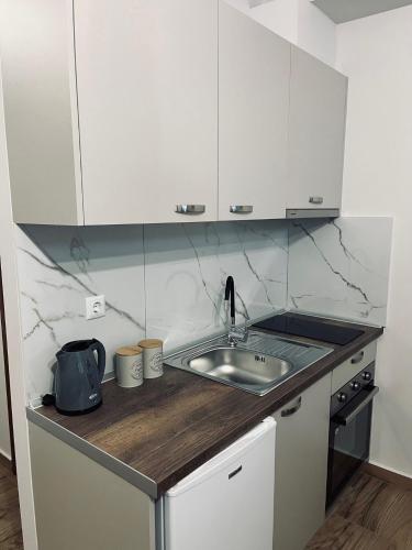 cocina con fregadero y armarios blancos en Paggaio Escape Apartments, en Nikísiani