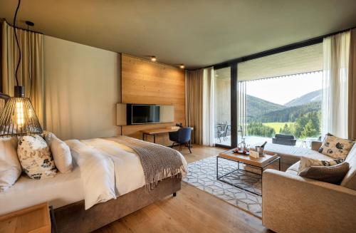 a bedroom with a large bed and a living room at Almwellness Hotel Pierer in Fladnitz an der Teichalm