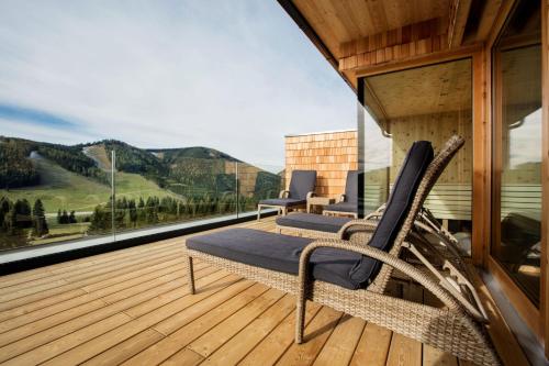a balcony with two chairs on a wooden deck at Almwellness Hotel Pierer in Fladnitz an der Teichalm