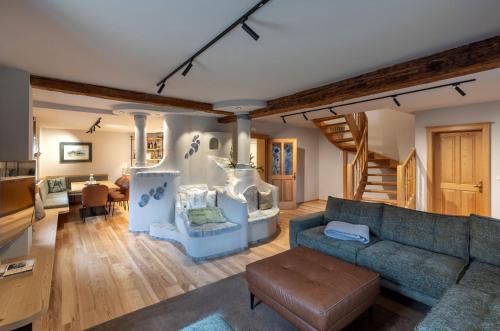 a living room with a blue couch and a staircase at Almwellness Hotel Pierer in Fladnitz an der Teichalm