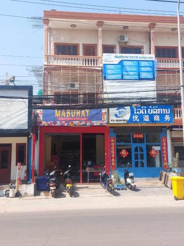 un bâtiment avec des motos garées devant un magasin dans l'établissement Mabuhay Guest House, à Vientiane