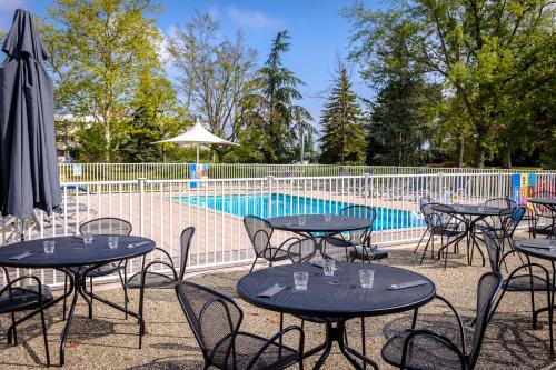 - un groupe de tables et de chaises à côté de la piscine dans l'établissement Novotel Mulhouse Bâle Fribourg, à Sausheim