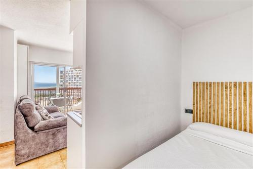 a bedroom with a bed and a couch and a balcony at Cosy Beach II in Empuriabrava