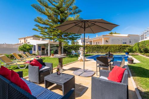a patio with chairs and an umbrella next to a pool at Villa Glamour by Portucasa in Armação de Pêra
