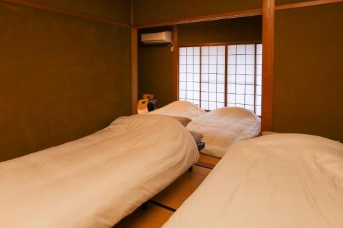 two beds in a room with a window at 1日1組限定の貸切の民泊です全館禁煙です屋外喫煙所無し間取りは2LDkです毎年12月8日から2月28日の駐車場は使用不可能です in Fukui