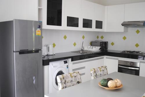 a kitchen with a washing machine and a bowl of fruit on a table at Phuket.Rent in Ban Klang
