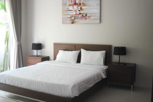 een slaapkamer met een bed met witte lakens en 2 lampen bij Phuket.Rent in Ban Klang