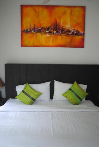 a bed with green and white pillows and a painting at Phuket.Rent in Ban Klang