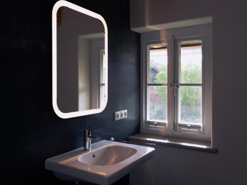 een badkamer met een wastafel, een spiegel en een raam bij Remark Studios - Apartment - Fachwerkhaus - Zentral in Burgwedel
