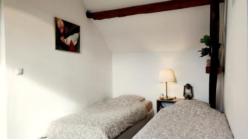 deux lits dans une chambre aux murs blancs dans l'établissement Studio équipé au sein d'une fermette, à Moncy