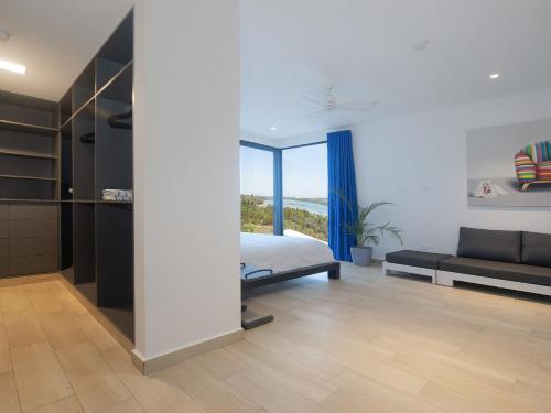 a bedroom with a bed and a couch and a window at Hermosa Bay Oceanview Villa in Boca Chica