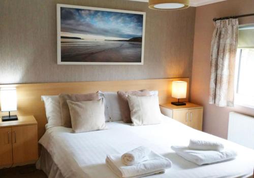 1 dormitorio con 1 cama blanca y 2 toallas en Mariners Lodge en Saint Minver