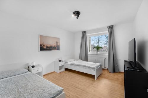 1 dormitorio con 1 cama, TV y ventana en Modernes Apartment mit Balkon, en Brunswick