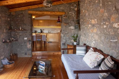 - un salon avec un canapé et un mur en pierre dans l'établissement Pappou's Traditional Cottage at Epano Elounda, à Elounda