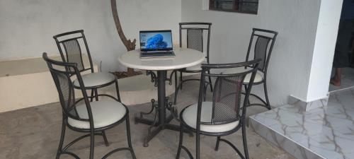 a table with four chairs and a laptop on it at SHIMBA SPRINGS MBUYU. ( Malindi) in Malindi