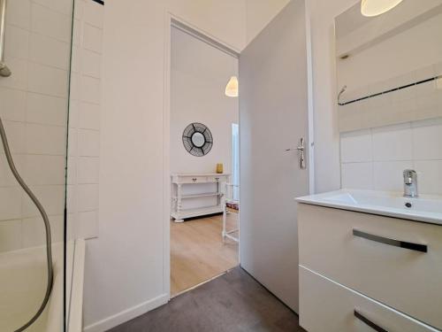 een witte badkamer met een wastafel en een spiegel bij Nairobi, Appartement Cosy in Reims