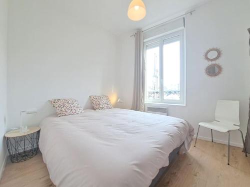 een witte slaapkamer met een groot bed en een raam bij Nairobi, Appartement Cosy in Reims