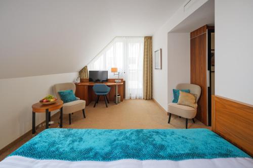 a bedroom with a bed and chairs and a desk at Hotel Silenzio in Prague