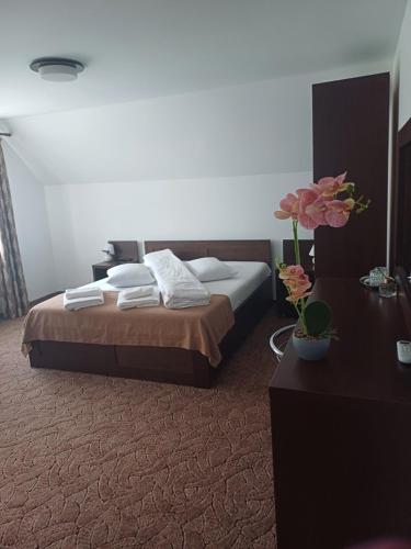 a bedroom with a bed and a table and flowers at Pensiunea Magura Ocnei in Tîrgu Ocna