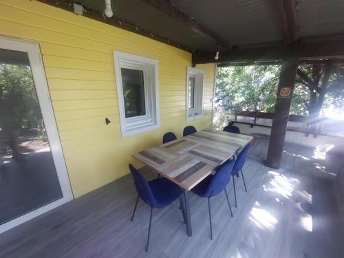 a wooden table and chairs on a porch with a yellow wall at T4 à 3mn à pied du lagon in Saint-Leu