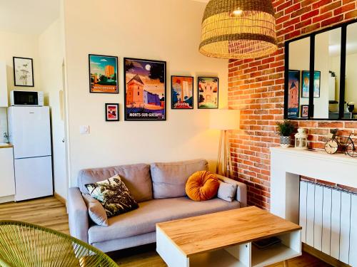 a living room with a couch and a brick wall at Gîte Clair de Lune in Monts-sur-Guesnes