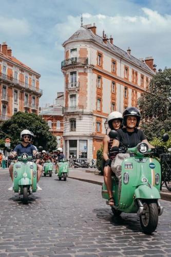 three people riding on green motorcycles down a street at *T2*Vue Garonne*Piscine*Garage* in Toulouse