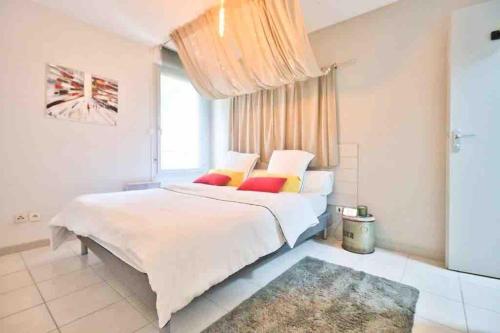 een slaapkamer met een groot wit bed met kleurrijke kussens bij *T2*Vue Garonne*Piscine*Garage* in Toulouse