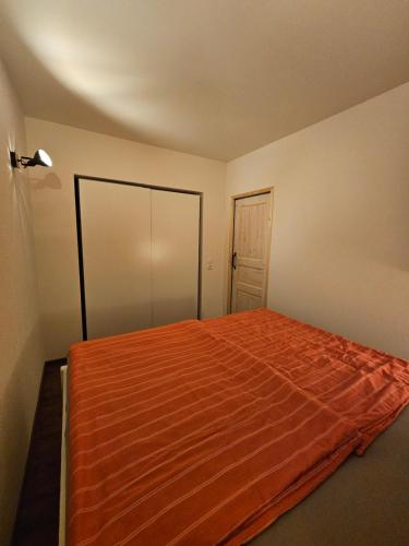 ein Schlafzimmer mit einem Bett mit einer orangefarbenen Decke in der Unterkunft Ferienwohnung Struppi Sächsische Schweiz in Struppen