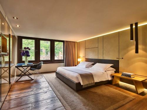Conservatorium Hotel في أمستردام: غرفة نوم بسرير كبير ومكتب