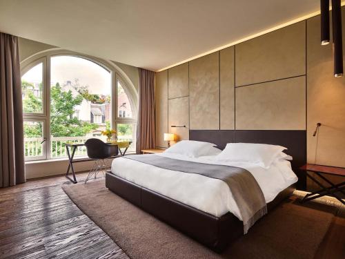 アムステルダムにあるConservatorium Hotelのベッドルーム1室(大きなベッド1台、大きな窓付)
