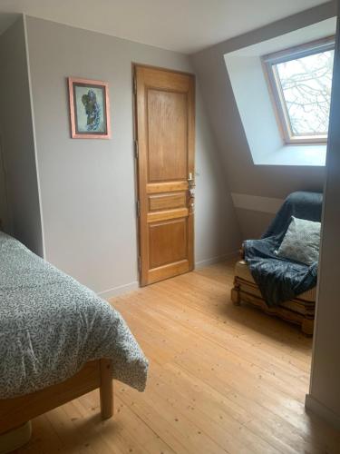 - une chambre avec un lit et une porte en bois dans l'établissement Appartement LES PAQUERETTES, à Janville