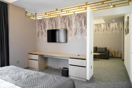 a bedroom with a desk with a tv on a wall at Dynasty Hotel & SPA in Yerevan