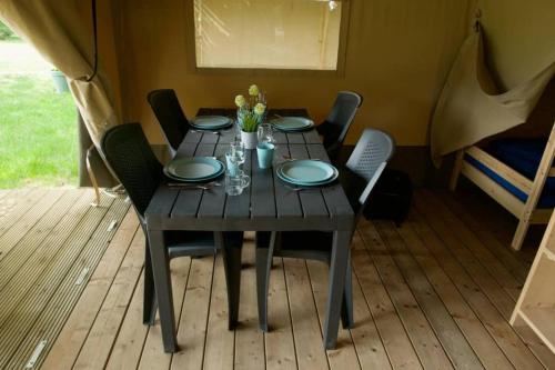 a wooden table with chairs and plates on it at Safaritent op groen en kindvriendelijk park op de Veluwe in Epe