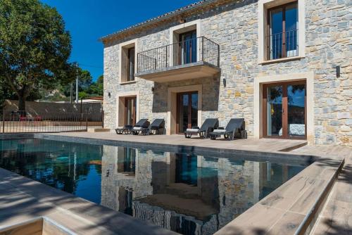 une maison en pierre avec une piscine en face de celle-ci dans l'établissement LA BASTIDE 5 étoiles Spa Saint Quenin Vaison - Pisicine - Jacuzzi Hammam MONT VENTOUX PROVENCE, à Vaison-la-Romaine