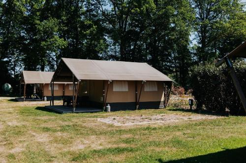 una tienda en un campo con árboles en el fondo en Safaritent op groen en kindvriendelijk park op de Veluwe en Epe