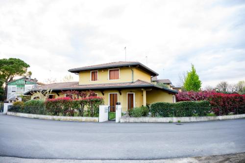 a yellow house with flowers in front of a street at Residence Stradella Verde in Staranzano