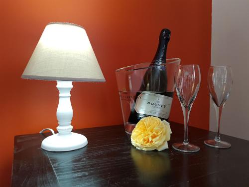 - une table avec une lampe, une bouteille de vin et deux verres dans l'établissement Domaine de l'Oie Rouge, à Les Rosiers