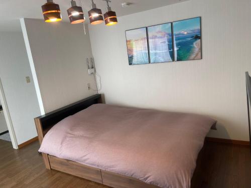 a bed in a room with two pictures on the wall at OKAERI築地町 in Takamatsu