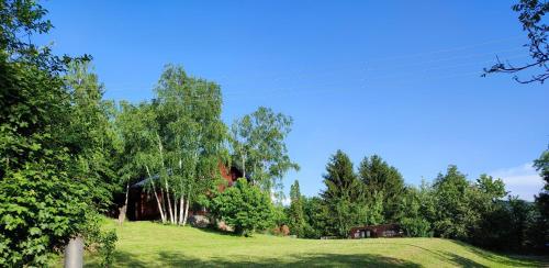 Šumarak Lodge في سراييفو: حقل أخضر مع أشجار و منزل على تلة