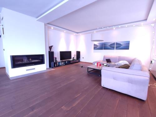 a living room with a white couch and a tv at Šumarak Lodge in Sarajevo
