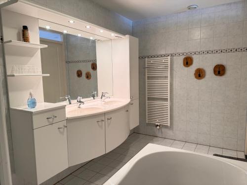 ein Badezimmer mit Badewanne, Waschbecken und Spiegel in der Unterkunft Callantsoger Staete 210 in Callantsoog