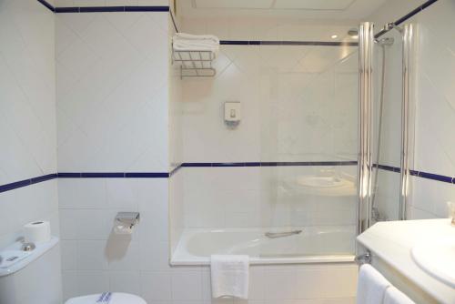 y baño con ducha, aseo y lavamanos. en TRH Ciudad de Baeza, en Baeza