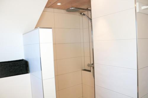 a shower in a bathroom with white tiles at Wolfsgrund Villa und/oder Apartment - Luxus in Seenähe mit tollem Garten in Schluchsee