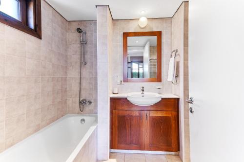 a bathroom with a bath tub and a sink at 2 bedroom Apartment Kalypso with private garden, Aphrodite Hills Resort in Kouklia