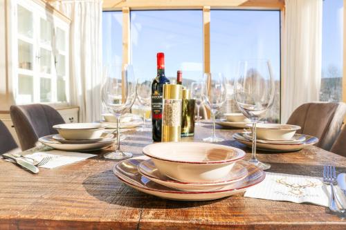 a wooden table with plates and wine glasses on it at Wolfsgrund Villa und/oder Apartment - Luxus in Seenähe mit tollem Garten in Schluchsee