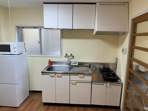 a small kitchen with a sink and a refrigerator at OKAERI築地町 in Takamatsu
