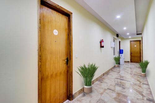 an office hallway with a wooden door and plants at Super Capital O Hotel Crestwood Inn in Dehradun