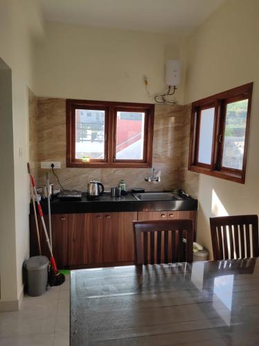 cocina con mesa, fregadero y 2 ventanas en Vacation villa, en Kodaikanal