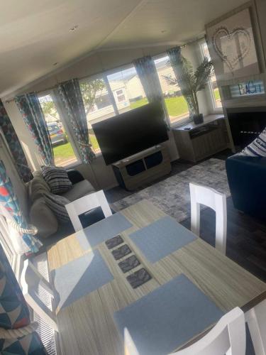 a living room with a flat screen tv and a table at CARAVAN NEL in Meliden