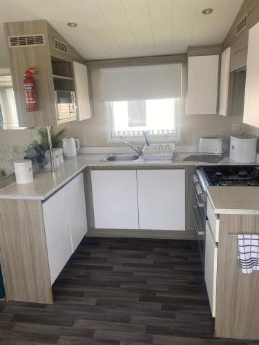 uma cozinha com armários brancos e um forno com placa de fogão em CARAVAN NEL em Meliden
